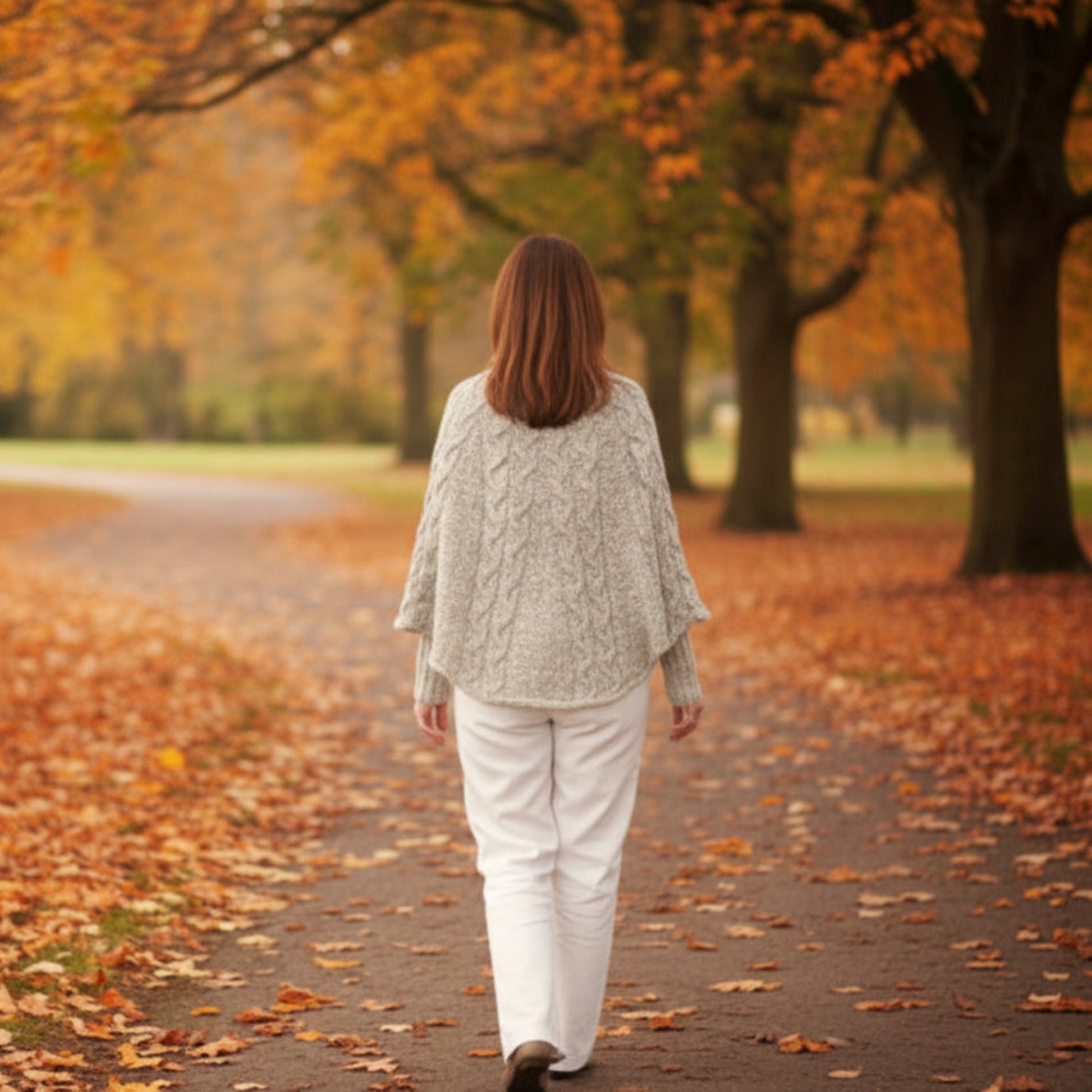 Person wearing a light beige poncho outdoors on a fall day