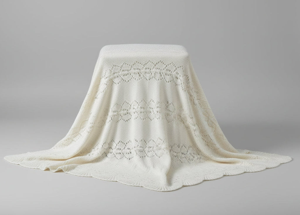 White lace christening blanket draped over a cylindrical object on a gray background