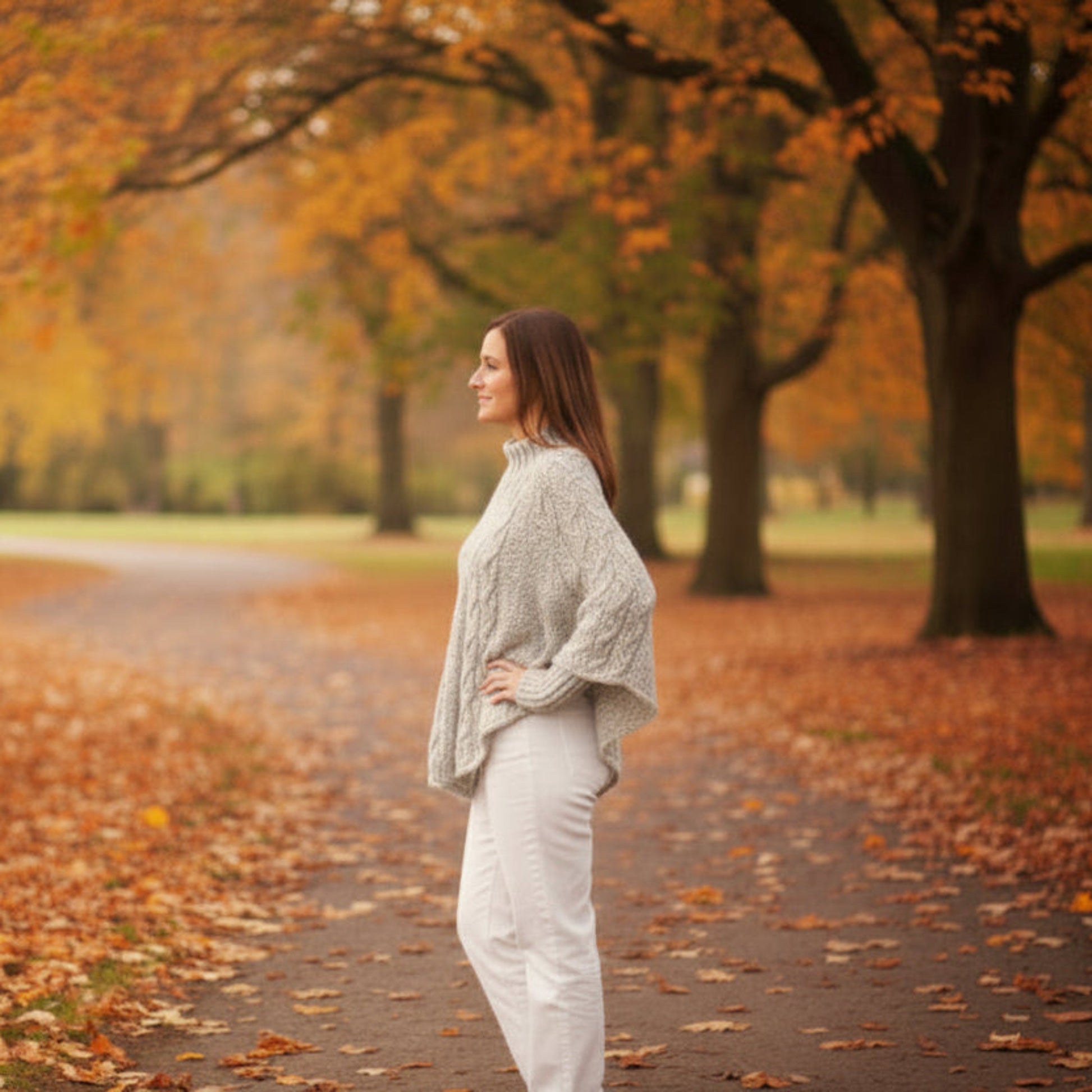 Woman walking down a path lined with trees with autumn foliage